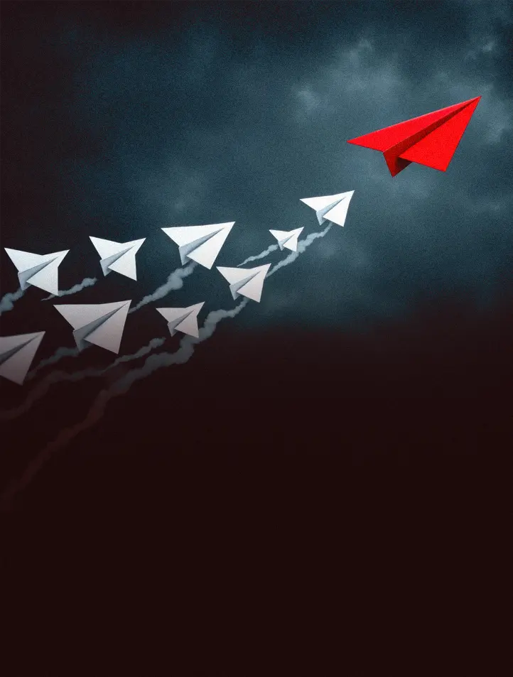 Aviões de papel brancos voando atrás de um avião de papel vermelho que lidera